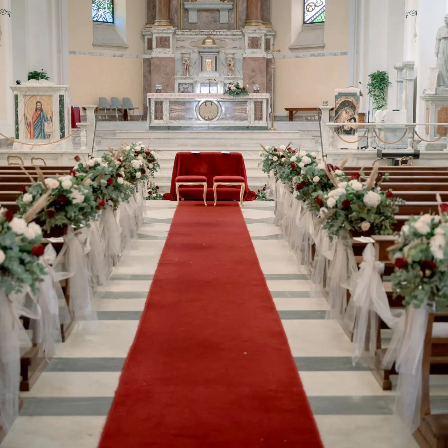 Navata della chiesa addobbata per il matrimonio con composizioni di rose rosse e bianche
