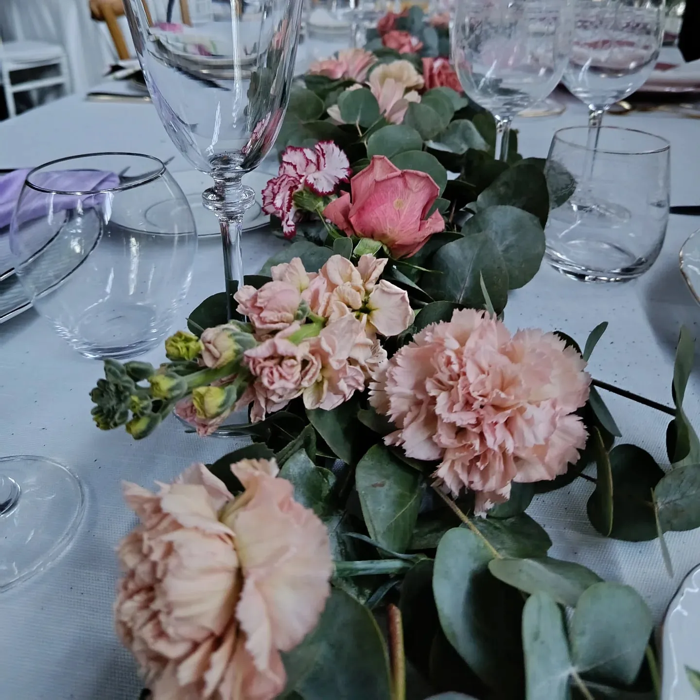 Runner floreale per il tavolo degli sposi con rose rosa, garofani ed eucalipto