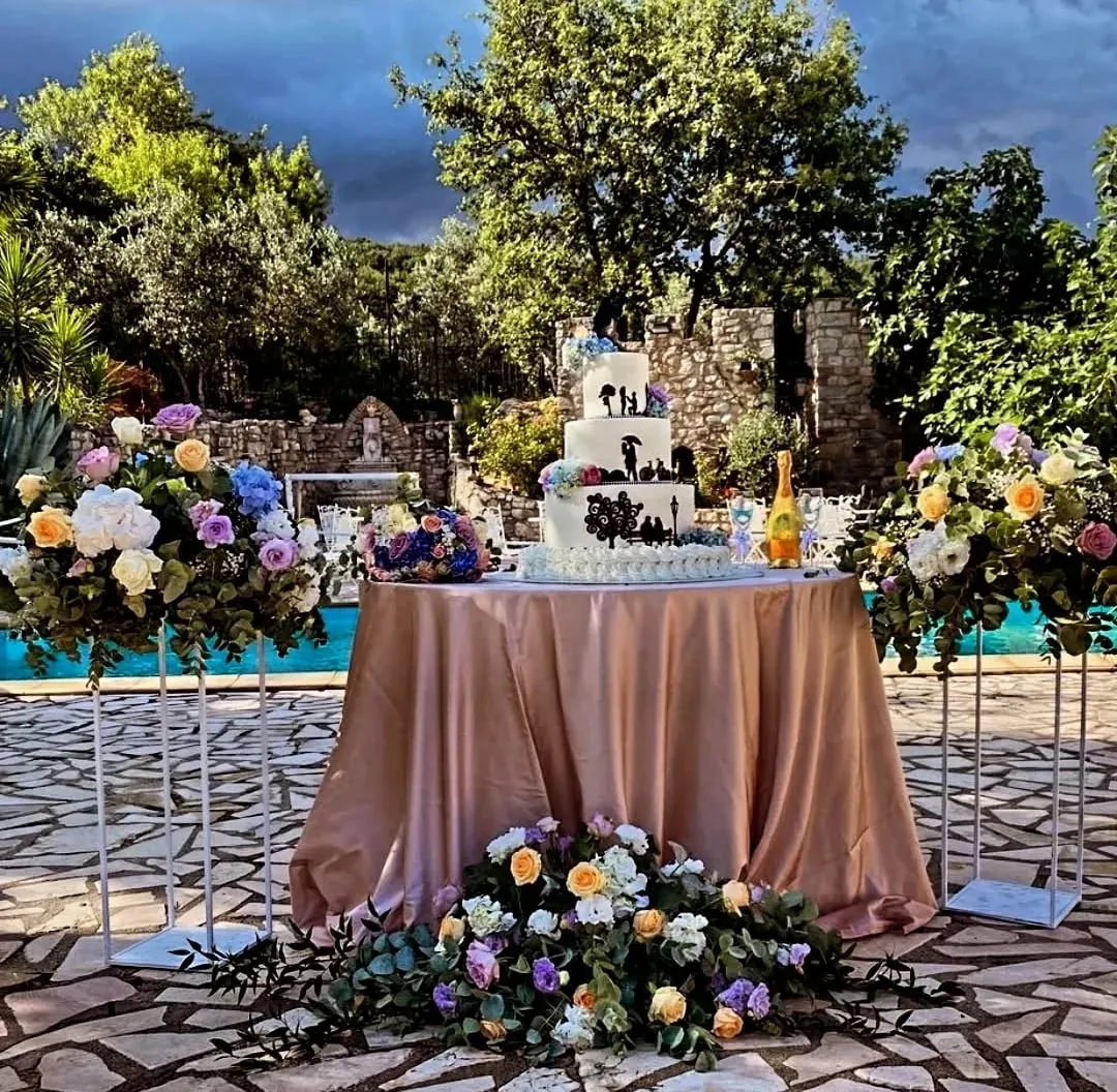 Tavolo nuziale a bordo piscina con tovaglia rosa e composizioni di fiori colorati