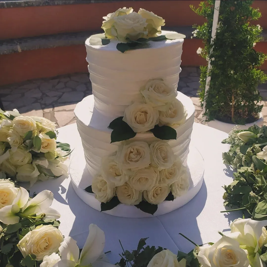 Torta nuziale bianca decorata con rose bianche fresche